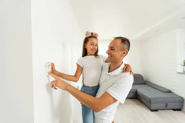 Controlling home with a digital touch screen panel installed on the wall in the living room. Concept of a smart home and mobile application for managing smart devices at home