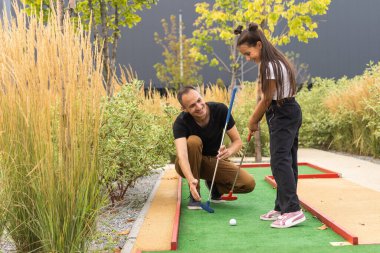 father and daughter playing mini golf.