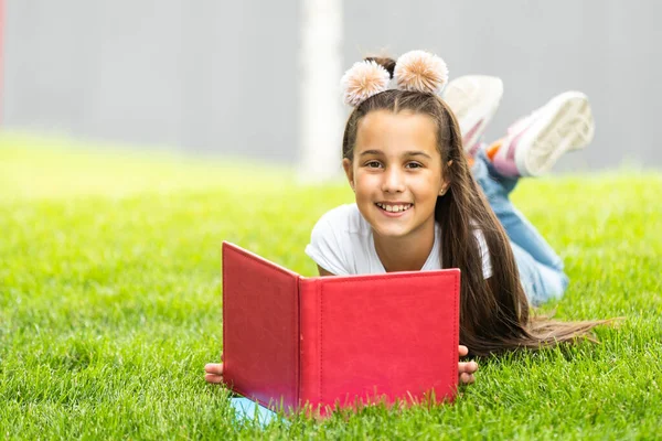 Little girl reading a book in the spring park.