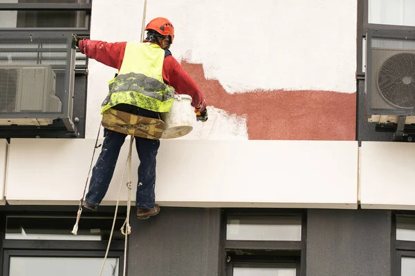 construction worker is painting a wall with a roller.