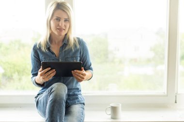 Tablet kadınların elindeydi. Hafif arkaplan. Mavi kot.