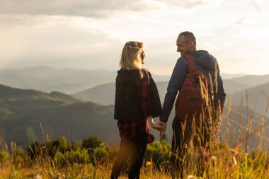 İki yürüyüşçü harika manzaralı bir dağın tepesinde dinleniyor.