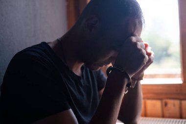 Mahkûm konsepti, hapisteki bir mahkumun elleri kelepçeli, erkek mahkumlar karanlık cezaevinde ağır şekilde zorlandı, şiddet