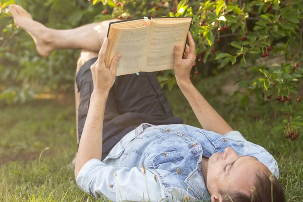 Young Man Lying Grass Relaxing Reading Book — Stockfoto