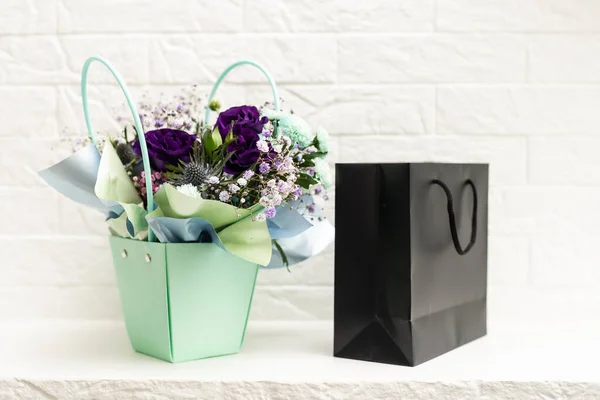 bouquet and black gift bag on white background