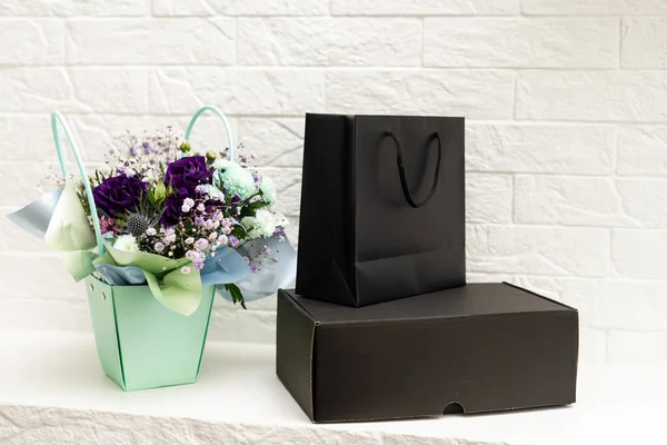 bouquet and black gift bag on white background