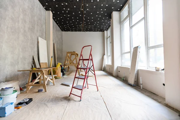 Aluminium ladder in a room under construction works. Repair process in an empty bright room. Empty interior for design, gray concrete wall. High quality photo