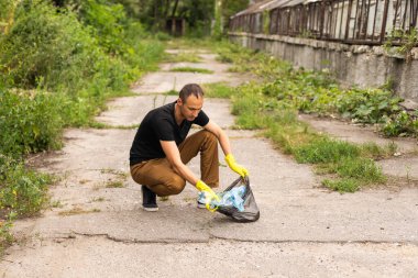 Genç gönüllü parktan plastik şişeleri topluyor..