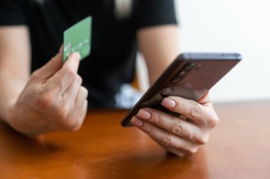 Genç bayan alışverişçi kanepeye oturup banka kartı telefonuyla internet üzerinden ürünlere kolay ödeme yapmanın keyfini çıkarıyor. Seyahat acentesi taşıma operatörünün internet sitesinde seyahat biletleri..