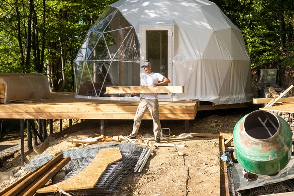 the master builds the dome. Outside spherical glamping dome. Hemispherical structure lattice shell geodesic polyhedron. Camping house hotel party tent