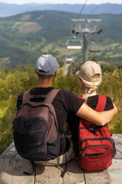 People sit on the ski elevator. View from the back. Summer, green forest. summer family vacation in the mountains