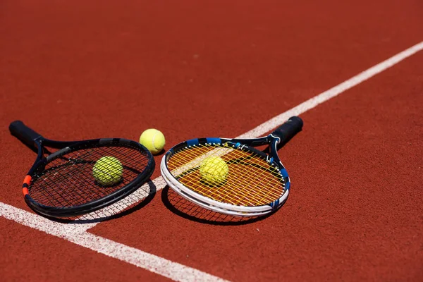 Tennis racquets with tennis balls on clay court