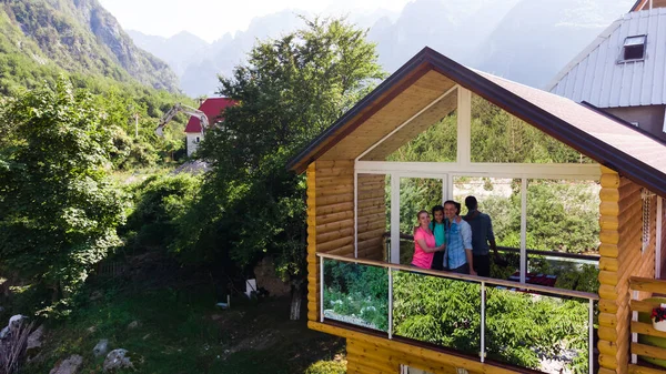 Aile dağ tepe tepe ve güneş üzerinde ahşap kulübe verandada.