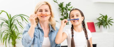 Anne ve kız güzel ve mutlu anneler günü için kağıt ve kalemlerle birlikte masaya oturarak bir kart yapın..