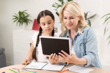 Anne ve kızı evde dijital tablet kullanıyorlar..