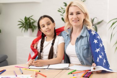 Vatansever bayram. Mutlu aile, anne ve kızı evde Amerikan bayrağı taşıyan kız çocuğu. ABD 4 Temmuz 'u kutladı