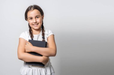 Esmer küçük kız, beyaz arka planda izole edilmiş bir kitap okuyor..