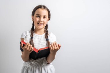 Esmer küçük kız, beyaz arka planda izole edilmiş bir kitap okuyor..