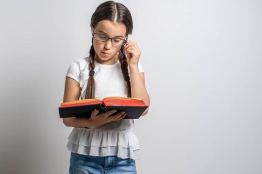 Esmer küçük kız, beyaz arka planda izole edilmiş bir kitap okuyor..