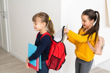 Konuşan ve sırlarını paylaşan iki küçük kız öğrenci. Eğitim, moda, arkadaşlık kavramı