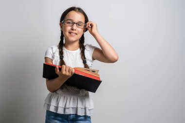 Esmer küçük kız, beyaz arka planda izole edilmiş bir kitap okuyor..