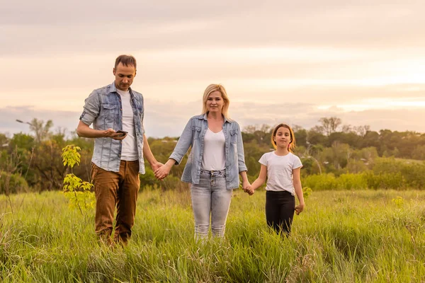 Mutlu aile: anne baba ve kız gün batımında doğada.