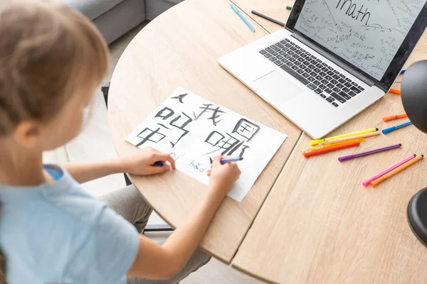 little girl learning chinese while using her laptop computer in the living room at home. family activity concept