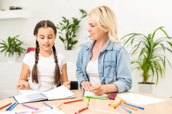 Sevgi dolu bir aile. Anne ve kızı çocuk oyun oynuyor ve ödev yapıyor.