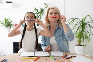 Anne ve küçük 8 'lerin kızı evde renklerle resim yaparken eğleniyorlar. Mutlu anne ya da dadı ve küçük kız çizimin keyfini çıkarın. Hobi konsepti