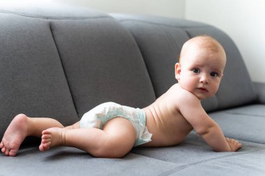 Altı aylık çocuk beyaz arka planda oturuyor..