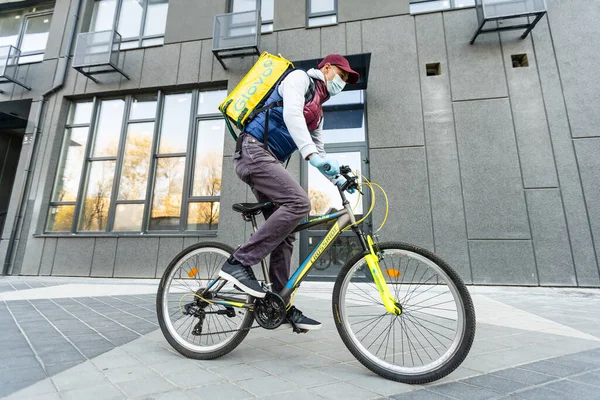 KIEV, UKRAINE - 28 Nisan 2021: Sokakta ünlü sarı kutusu ve bisikleti olan Glovo dağıtım elemanı. Bisikletli servis elemanı.