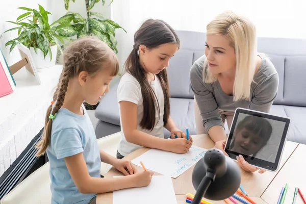 Anne ve iki kız evde ödev yapıyor ve kitap okuyor..