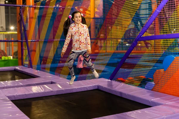 Sıradan kıyafetler içinde zıplayan ve gülümseyen neşeli bir kız..