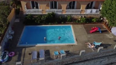 Anne ve küçük kızı havuzda eğleniyor. Annem çocukla oynuyor. Aile yüzme havuzunda yaz tatilinin tadını çıkarıyor.