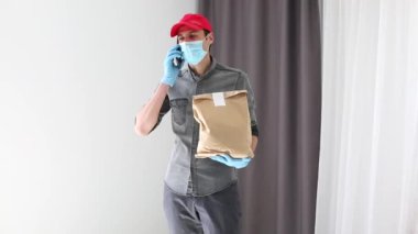 Maske takan ve koruyucu eldiven takan bir kurye paket teslim eder. Bir salgında çalışmak
