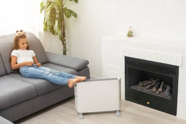 little girl near the heater. Energy crisis.