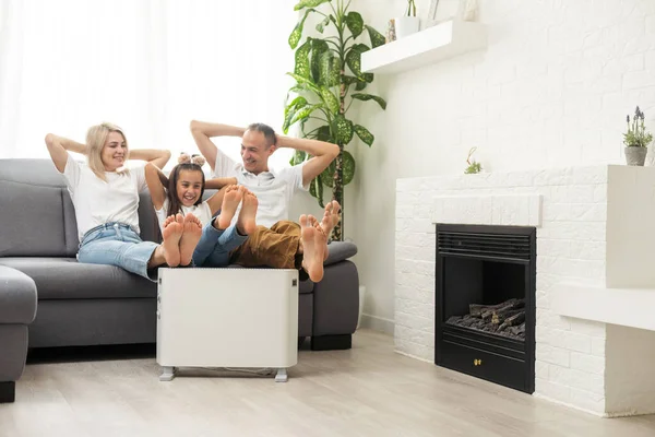 Family warming near electric heater at home