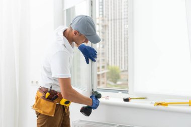 Eldivenlerde uzman. PVC pencerelerini tornavidayla kapatıyor. Plastik pencere onarım ve bakım konsepti kurulumu