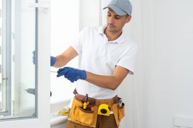 a repairman repairs, adjusts or installs metal-plastic windows in the apartment. glazing of balconies, loggias, verandas in house. production of double-glazed windows to individual sizes