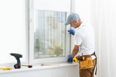 Usta plastik bir pencereye çift camlı yeni bir pencere takar.