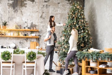 Mutlu Noeller ve mutlu tatiller. Anne, baba ve kız Noel ağacı süslüyorlar.