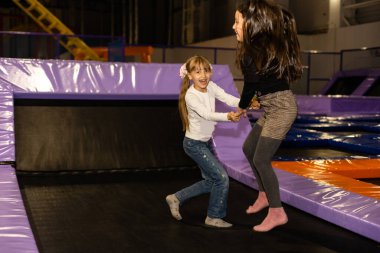Little pretty girls having fun. Jumping on trampoline in children zone. Amusement park.