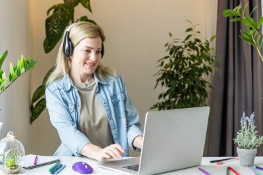 Bilgisayarda uzaktan kumandalı derslerde öğretmenlik yapan, öğrencileri dinleyen, okul sınıfında ödev yazan genç öğretmen.