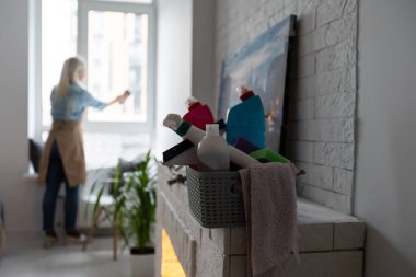 Ev hanımı pencereye deterjan püskürtür ve pencereyi temiz bir mikrofiber bezle siler. Çizgileri olmayan şeffaf pencereler. Kadın Temizlik Evi konsepti