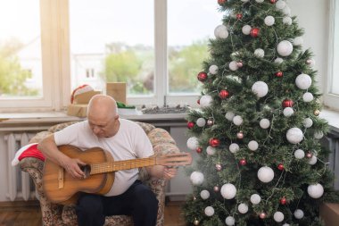 Mutlu insanlar aile kavramı - Yaşlı son sınıf öğrencisi Noel 'de evdeki koltukta gitar çalıyor..