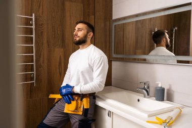 Professional plumber with plunger and instruments near sink
