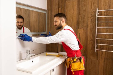 İşçi aynayı banyoya yerleştirir.