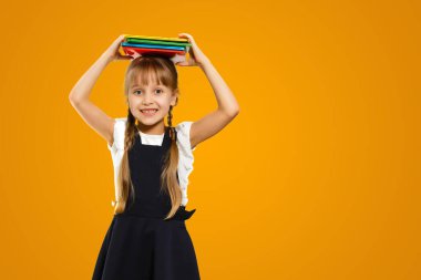 Cropped close up shot of a happy smart caucasian teenager schoolgirl pupil student wearing bag going back to school for new academic educational year isolated in yellow background