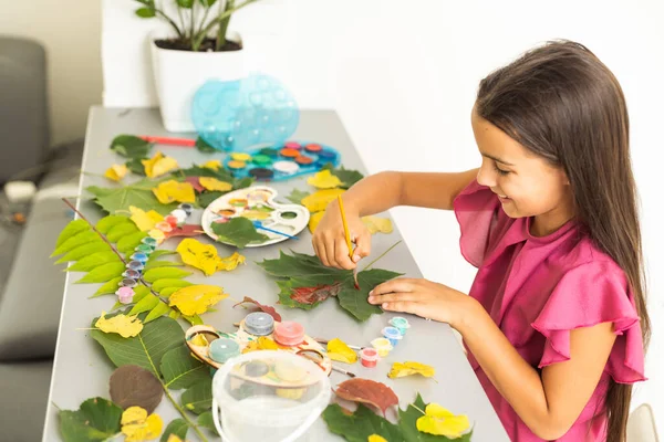 female hands paint autumn leaves on canvas with paints outdoor. High quality photo