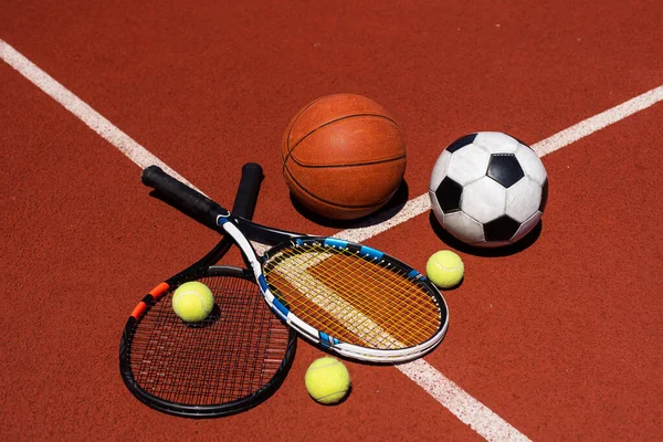A group of sports equipment on black background including tennis, basketball, and soccer and boxing equipment on a background with copy space.